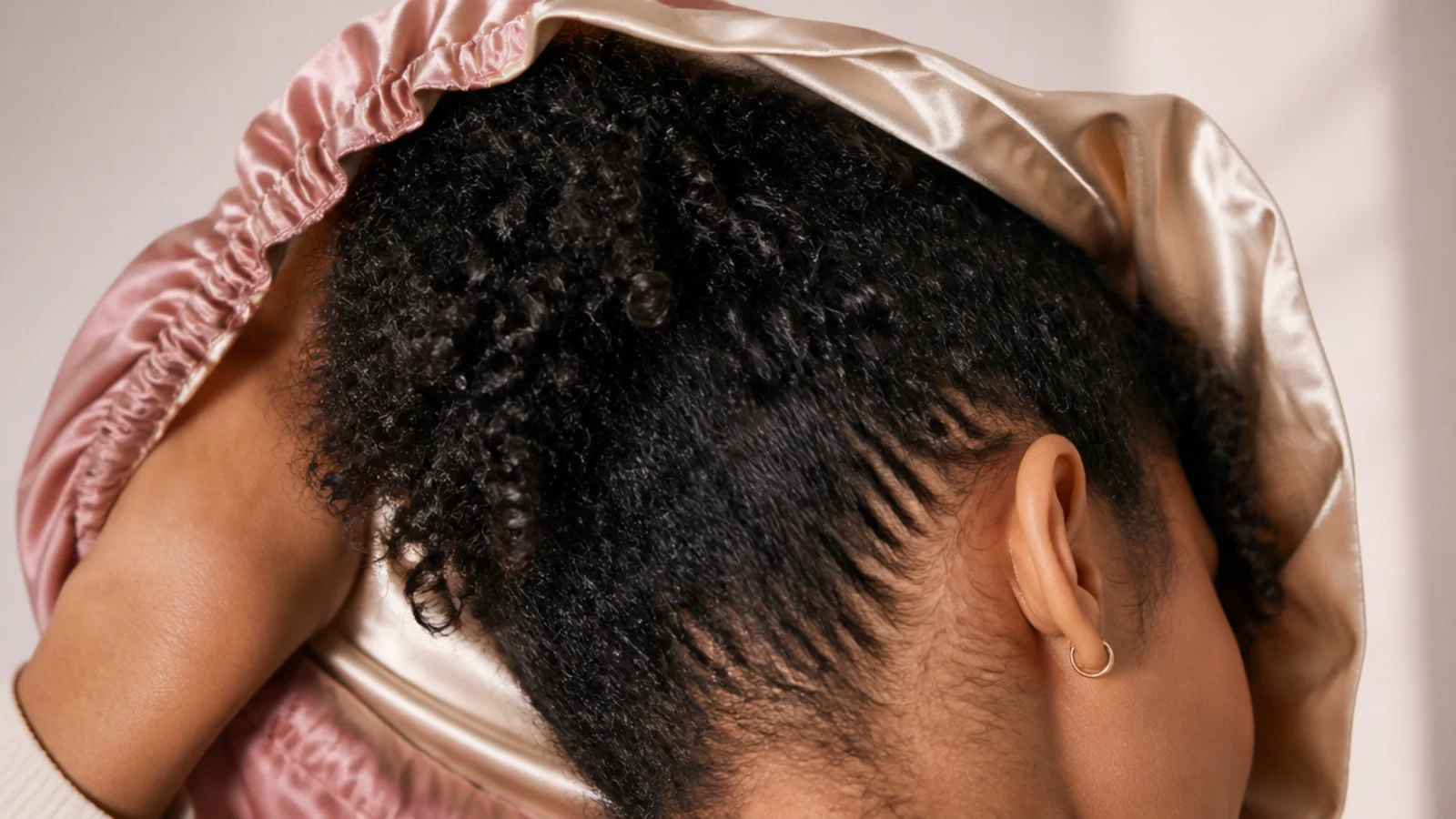 A satin bonnet covering gathered hair before bed