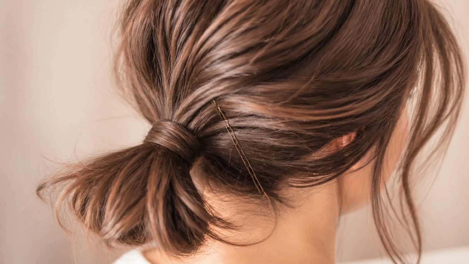 A bob gathered into a small low ponytail with shorter pieces pinned
