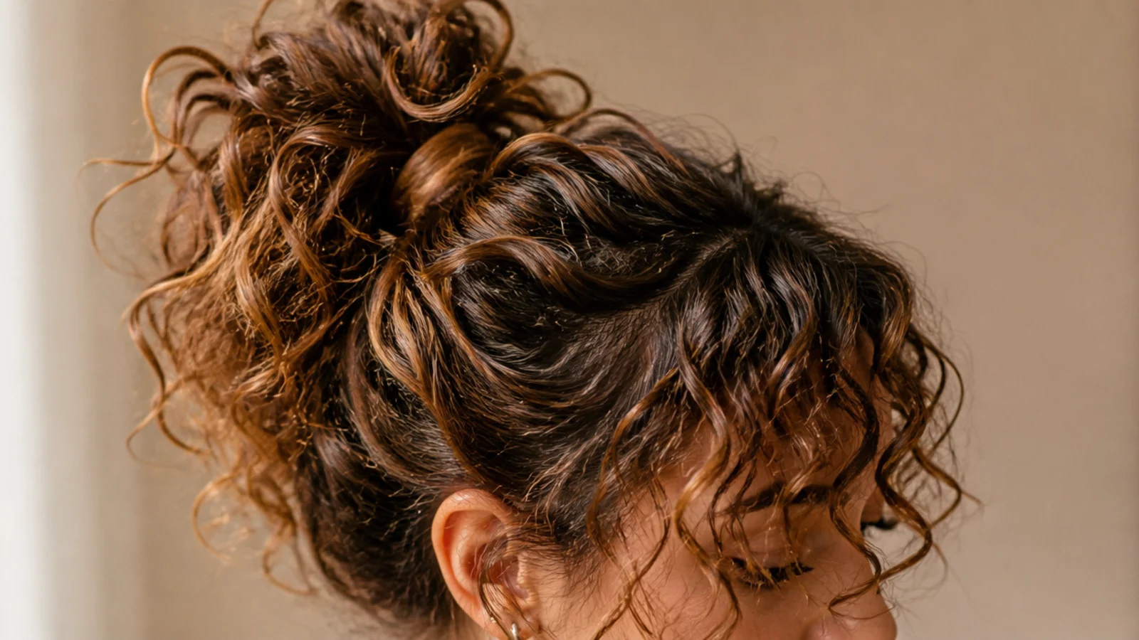 A curly fringe above curls gathered into a high pineapple