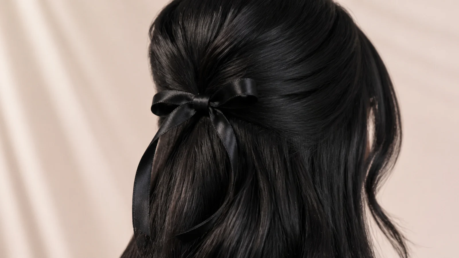 Black hair worn half up and finished with a satin bow