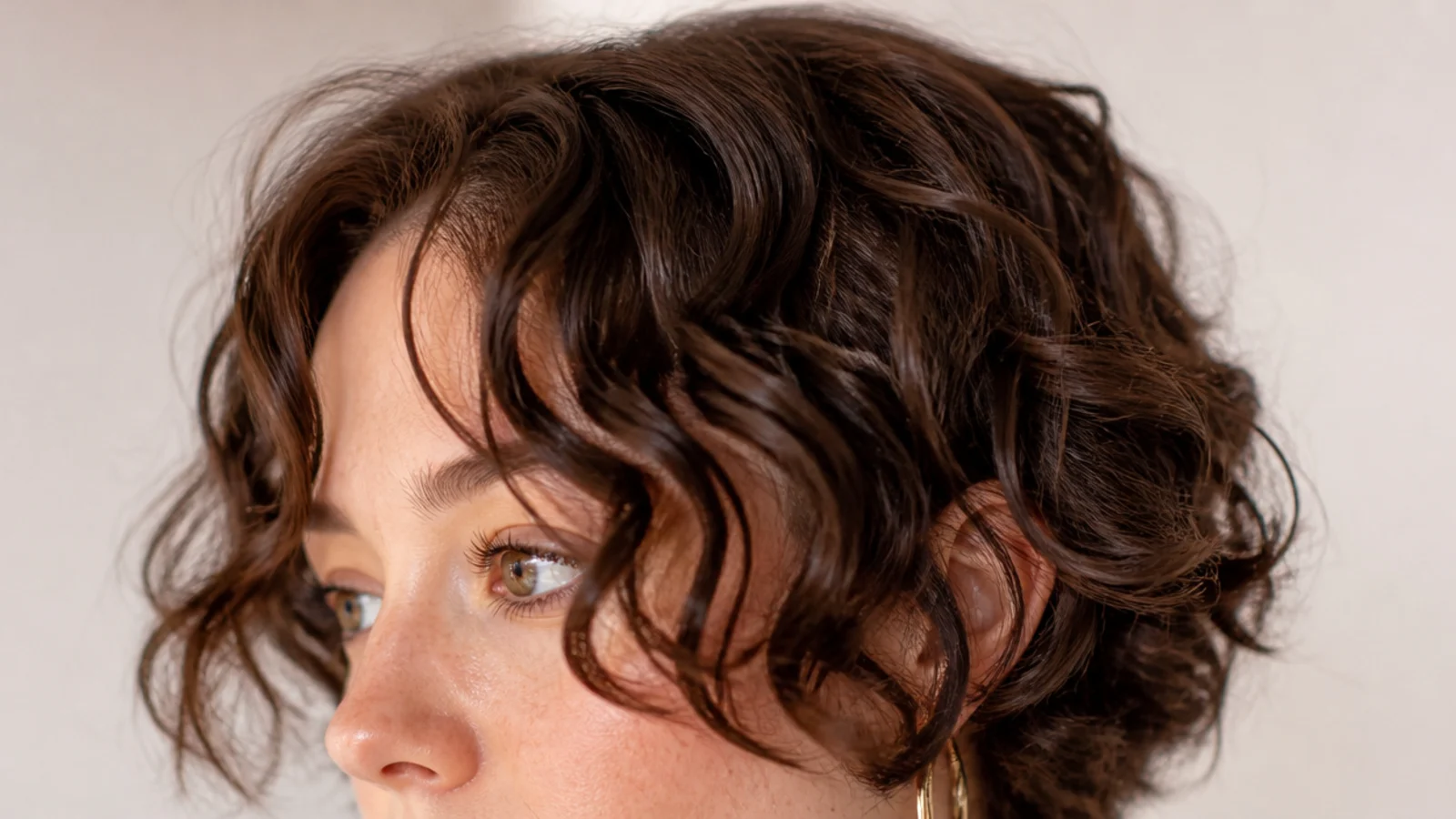 A curly curtain fringe with long outer pieces falling past the cheekbones