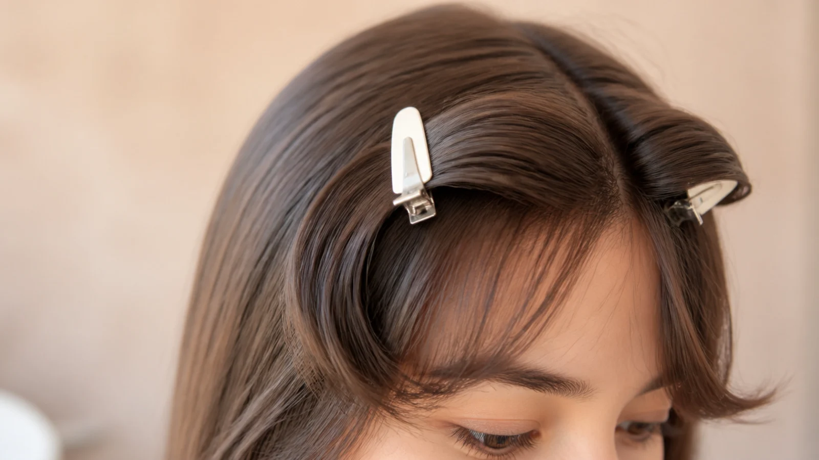 Two flat metal clips holding damp front sections across the top of the head
