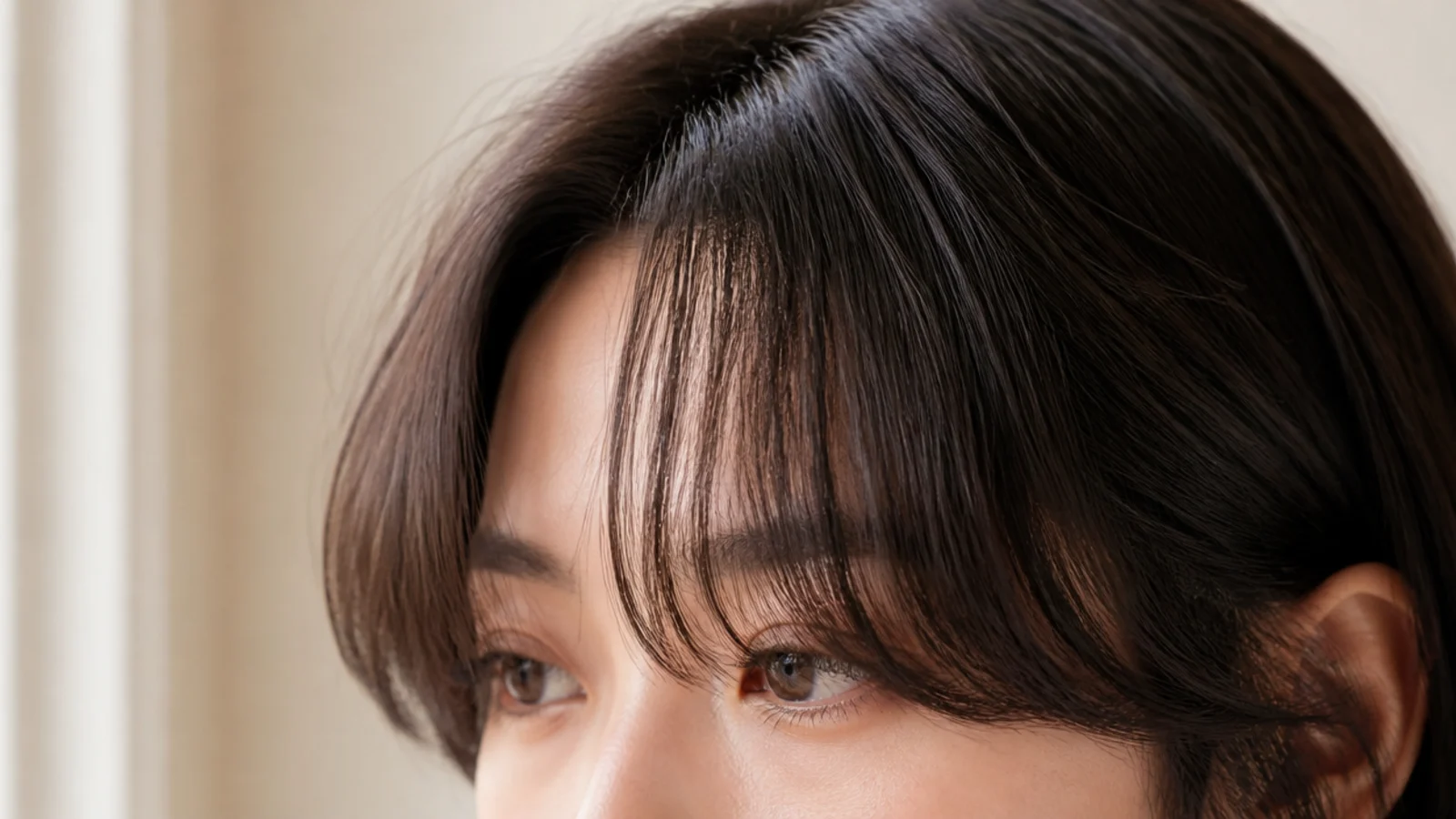 Dense dark hair with a softened split fringe falling to both sides